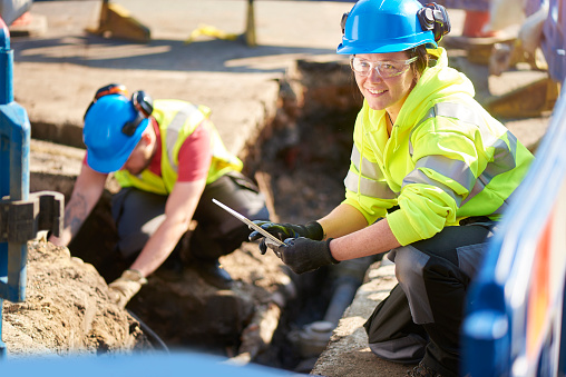 a female gas engineer holds a new gas valve as she and a colleague prepare to replace the old pipework in a residential uk street .