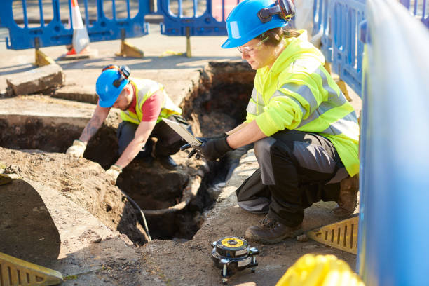 female gas ananlyst a female gas engineer holds a new gas valve as she and a colleague prepare to replace the old pipework in a residential uk street . laying underground pipes stock pictures, royalty-free photos & images