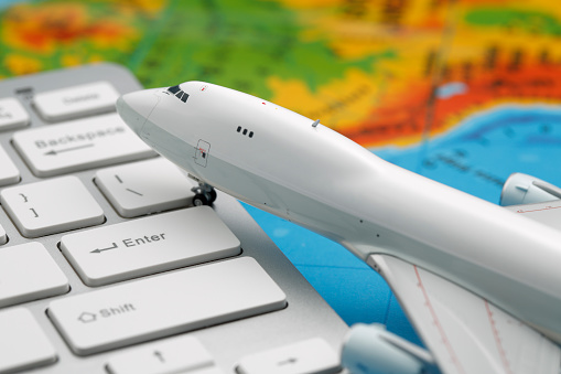 Model airplane on computer keyboard with map background