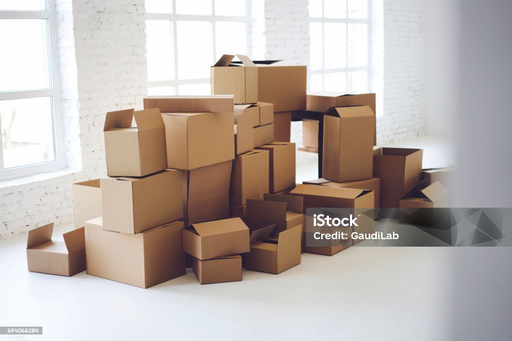 Carton boxes full of office goods stacked New white loft interior, relocation in new flat. Delivery or packaging service. Cardboards with mock up copy space for brand company information or logo Office Stock Photo