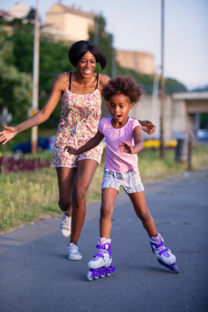 istock Mother assisting her daughter while roller skating at sunset. 694072436