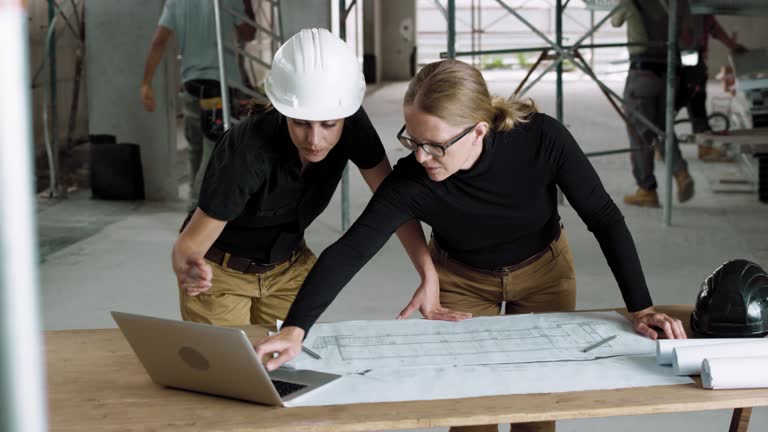 Female architect and female construction coordinator checking the plans at the construction site
