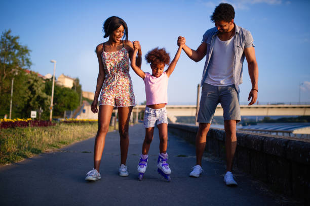 istock Parents assisting their daughter while roller skating at sunset. 694076354