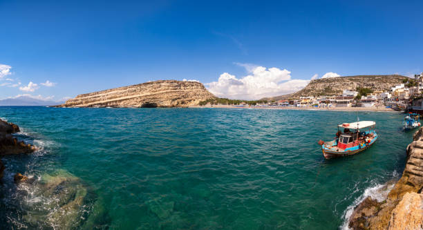 Panoramic view of Matala beach and lagoon with sandstone cliffs and turquoise waters of the Libyan Sea near Heraklion in Crete,  Greece, Mediterranean