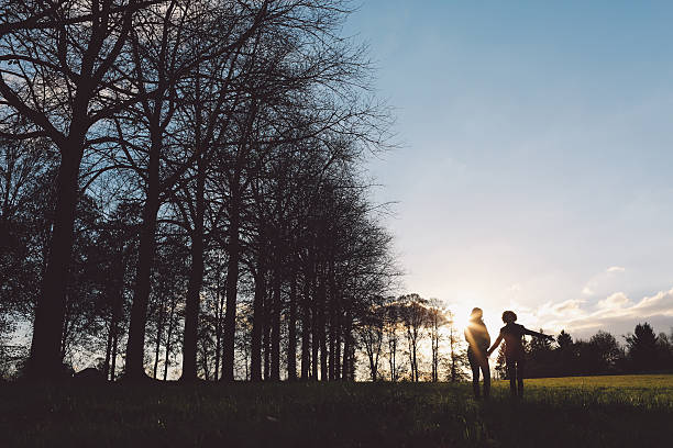 istock Low Angle View Of Couple By Silhouette Trees Against Sky 694086023