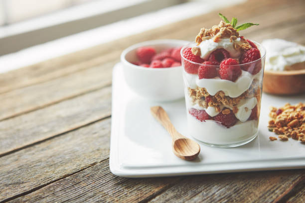 Shot of of granola, yoghurt and berries in a glass and on a plate