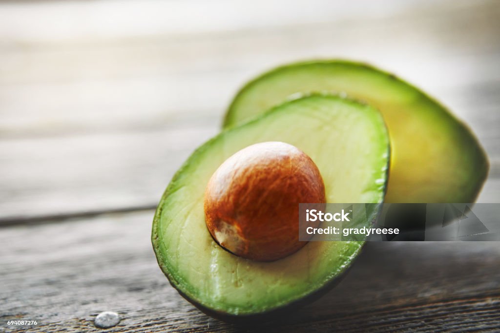 They're high in the healthy kind of fats Shot of a sliced avocado on a table Avocado Stock Photo