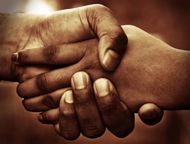 Hand shake of a child and an adult in sepia