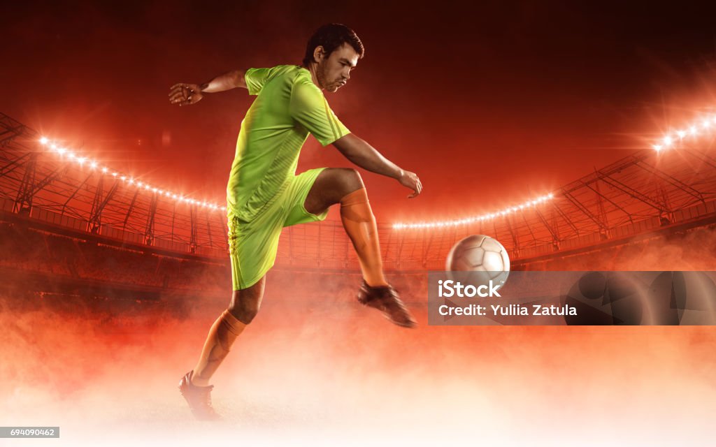 soccer player hits a ball on a soccer field soccer player hits a ball on a soccer field on red smoke background Red Background Stock Photo