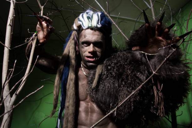istock Werewolf with long nails and crooked teeth among the branches of the tree 694090880