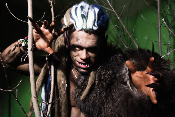 istock Werewolf with long nails and crooked teeth among the branches of the tree 694090886