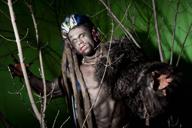 istock Werewolf with long nails and crooked teeth among the branches of the tree 694090894