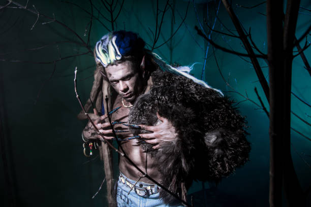 Muscular werewolf with dreadlocks with long nails among the branches of the tree.