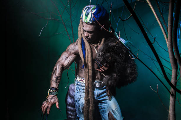 istock Muscular werewolf with dreadlocks with long nails among the branches of the tree. 694090910
