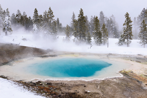 Turquoise blue water in Yellowstone National Park on snowy winter day.