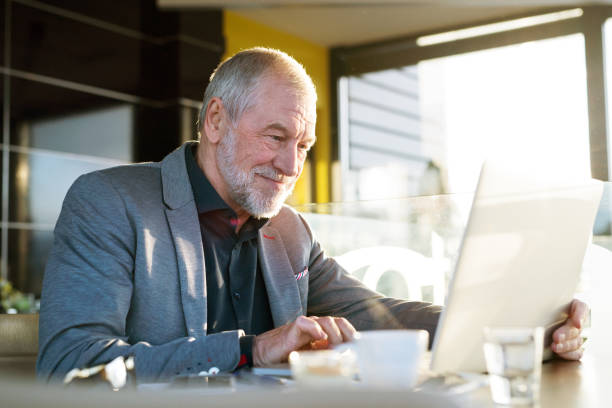 istock Senior businessman working on laptop in cafe 694105526