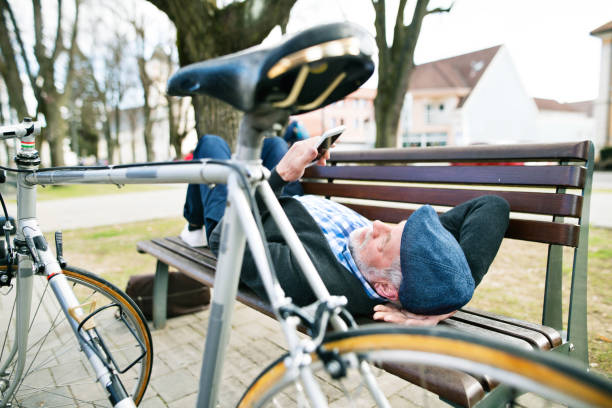 istock Senior man with bicycle in town, holding smart phone, texting 694106008