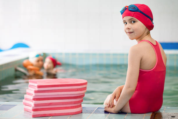 bambino seduto in piscina - wading child water sport clothing foto e immagini stock