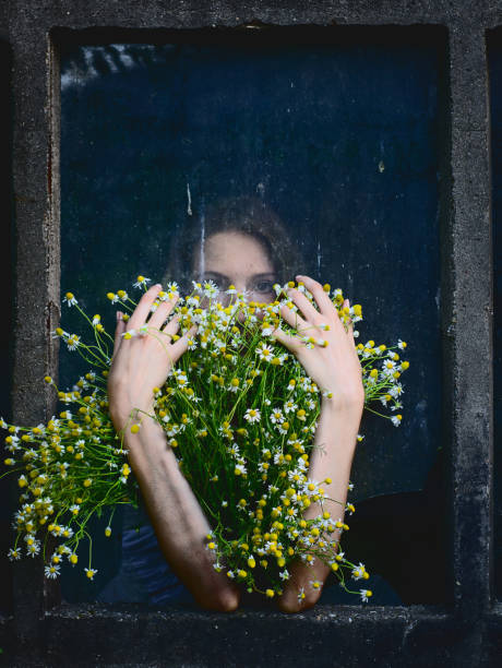 retrato de hermosa niña con ramo de flores de manzanilla al frente de la ventana rota - broken window glass women fotografías e imágenes de stock