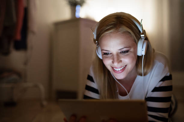 istock Woman lying on the floor, working on tablet at night. 694113902