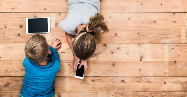 niños jugando con el jefe de dispositivos móviles - diferencia entre generaciones fotografías e imágenes de stock