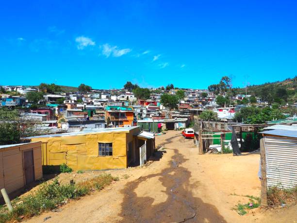 rua dos assentamentos informais coloridos, cabanas feitas de metal no township ou cape flats de stellenbosch, cidade do cabo, áfrica do sul com céu azul e o fundo de nuvens. - rural africa - fotografias e filmes do acervo