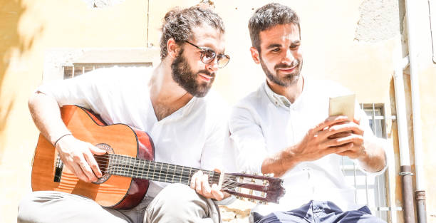 istock Two adult men playing guitar and taking a selfie 694138120