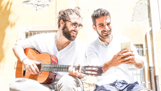 istock Two adult men playing guitar and taking a selfie 694139088