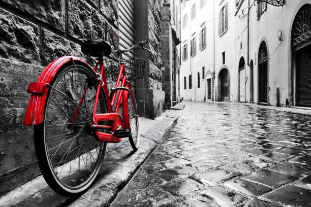 Retro vintage red bike on cobblestone street in the old town. Color in black and white. Old charming bicycle concept.