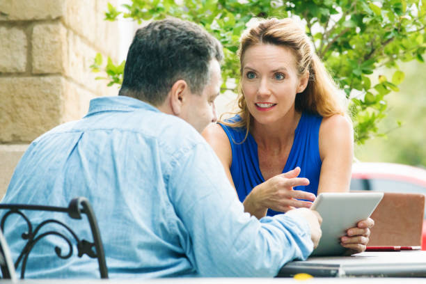 istock Mature Female executive persuades male colleague using tablet 694146234