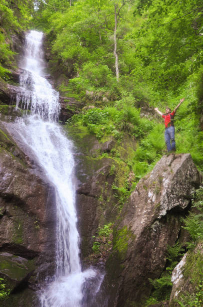 istock Man in wild nature. Man under a waterfall. 694149032