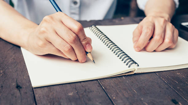 istock Woman hand writing note pad on wood table in coffee shop. 694156358