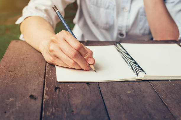 istock Woman hand writing note pad on wood table in coffee shop. 694156398