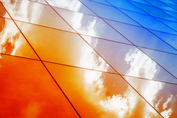 istock Modern glass architecture with reflection of red and blue sunset sky. Dramatic bright color. Vintage style background. 694168032