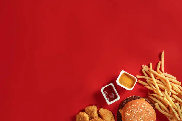 Photo of Burger and Chips. Hamburger and french fries in red paper box. Fast food on red background