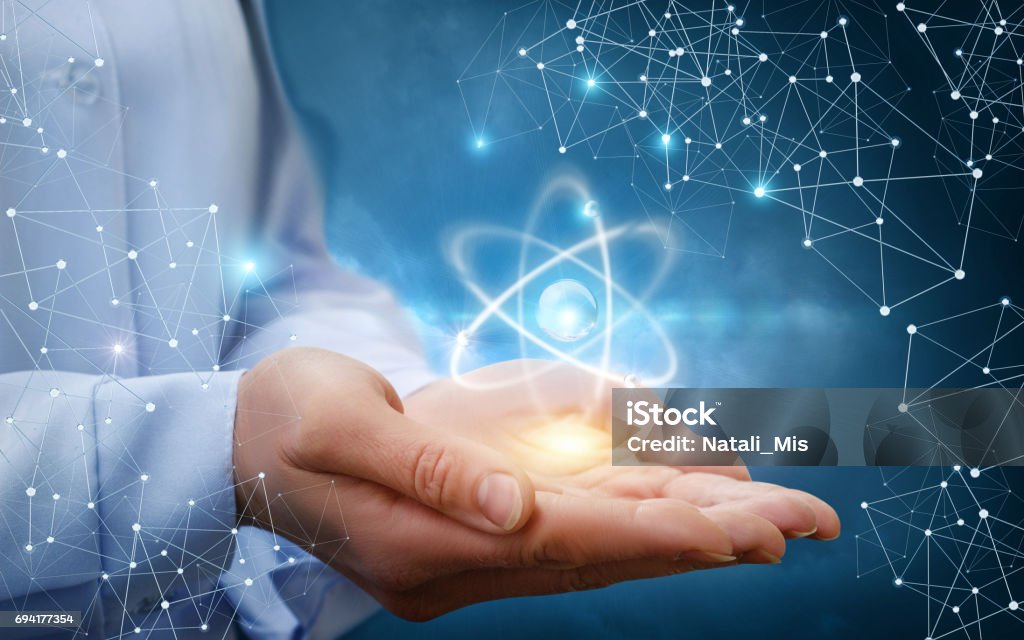 Atom molecule in female hands. Atom molecule in female hands on a blue background. Physics Stock Photo