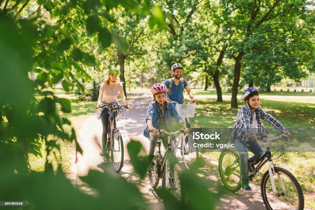 Family riding bicycle Family riding bicycle in the public park together. Cycling and enjoying the sunny day Family Stock Photo