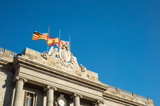 Detail of Facade of Barcelona's City Council with flags flying at half mast as a sign of mourning.