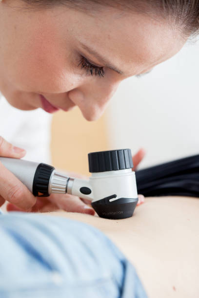 istock Dermatologist Inspecting Patient Skin Moles with Dermatoscope 694181892
