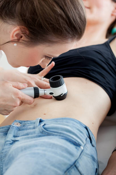 istock Dermatologist Inspecting Patient Skin Moles with Dermatoscope 694181898