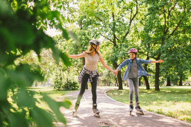 Family roller skating Family roller skating in the public park together. Mother and daughter holding hands and enjoying inline skating stock pictures, royalty-free photos & images