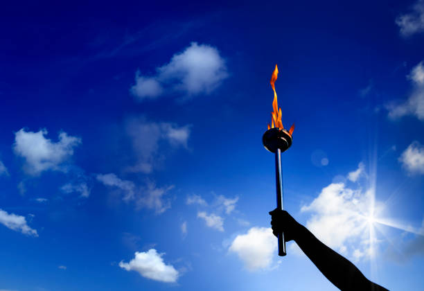 A close-up of a flame atop a cylindrical object with smoke against a dark background