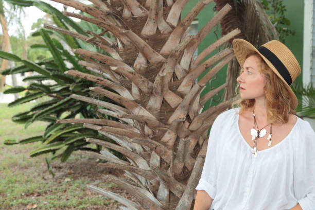 istock Young woman is standing on front of palm trunk. 694192408