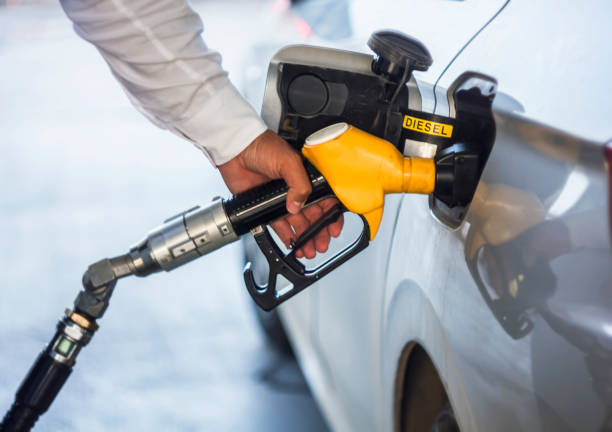 mão de homem segurando a bomba de gasolina amarelo - diesel - fotografias e filmes do acervo