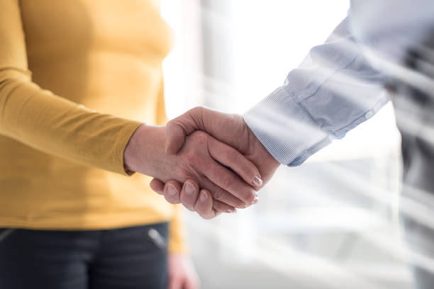 istock Woman and man shaking hands in office, light rays effect 694202200