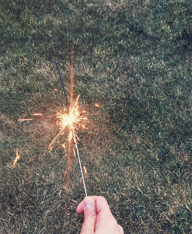 holding a sparkler on the grass to celebrate america's independence day on july 4th