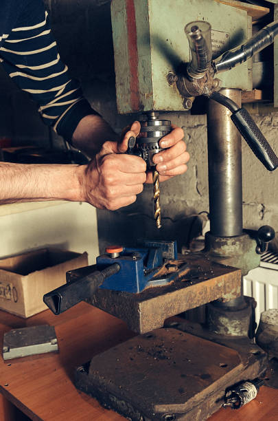 istock The worker in his garage works on a drilling machine. In the frame, a person's hands 694210244