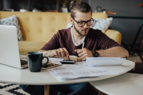 istock Concentrated young student using online banking to pay the bills 694221398