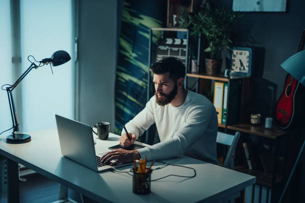 istock Handsome photo editor working late from home office 694229972