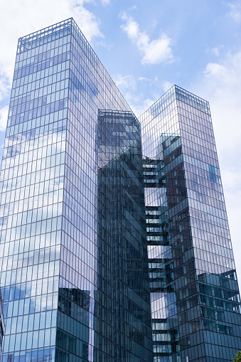 A view of modern glass buildings with clouds reflected on it
